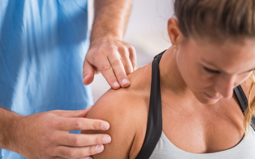 Physical therapist addressing a patient's trapezius muscle.